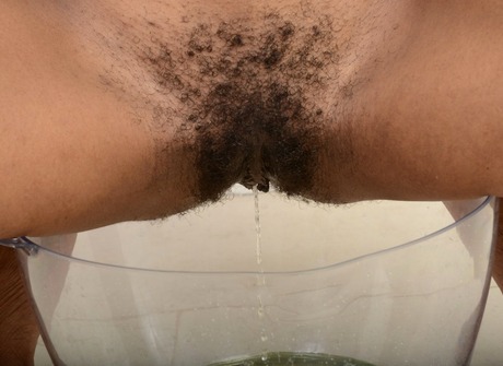 Tempting Kahlista strips and spreads her hairy pussy to piss