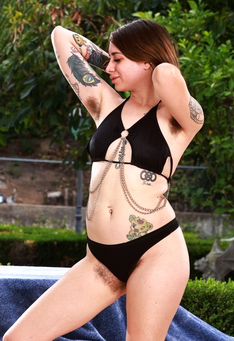 Furry tattooed babe Pearl Sage undressing and spreading hairy pussy