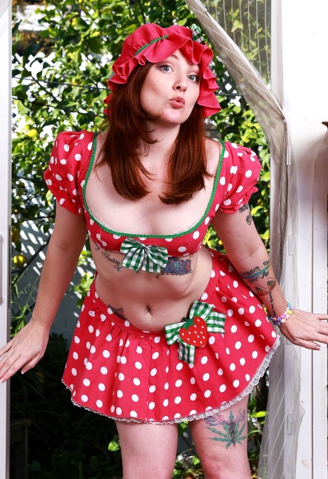 Redhead Kitty Strange strips polka dot outfit to reveal various tattoos and hairy pussy